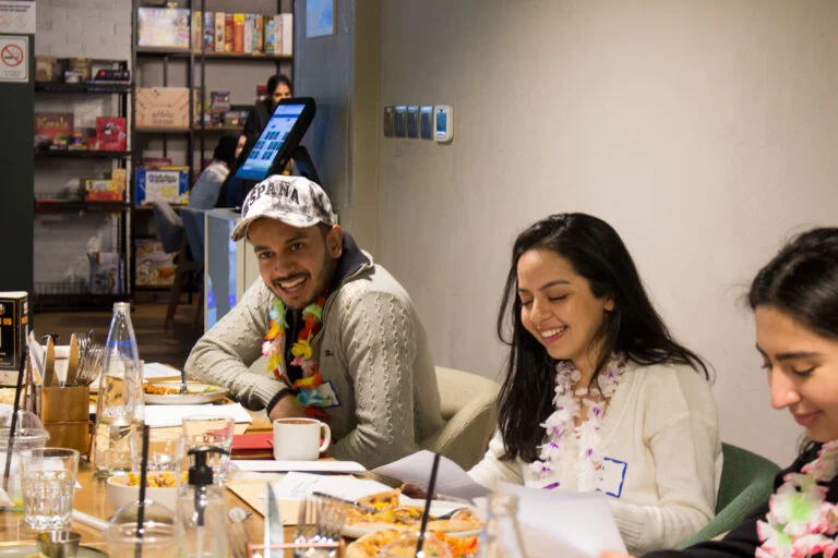 Guests laughing around a board game with an Unwind Game Master
