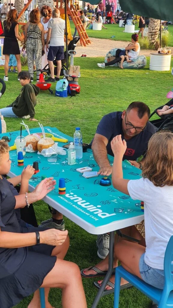 A family playing a board game at an Unwind game table outdoors