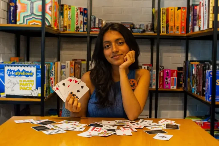 A guest holding a hand of cards at Unwind board game café